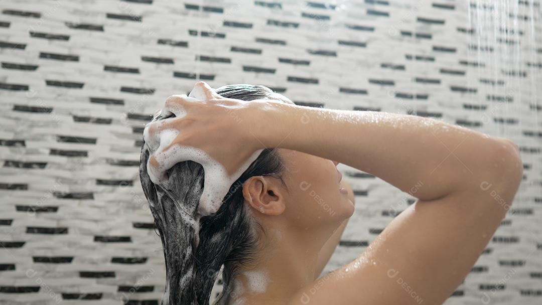 Jovem tomando banho e lavando o cabelo no banheiro