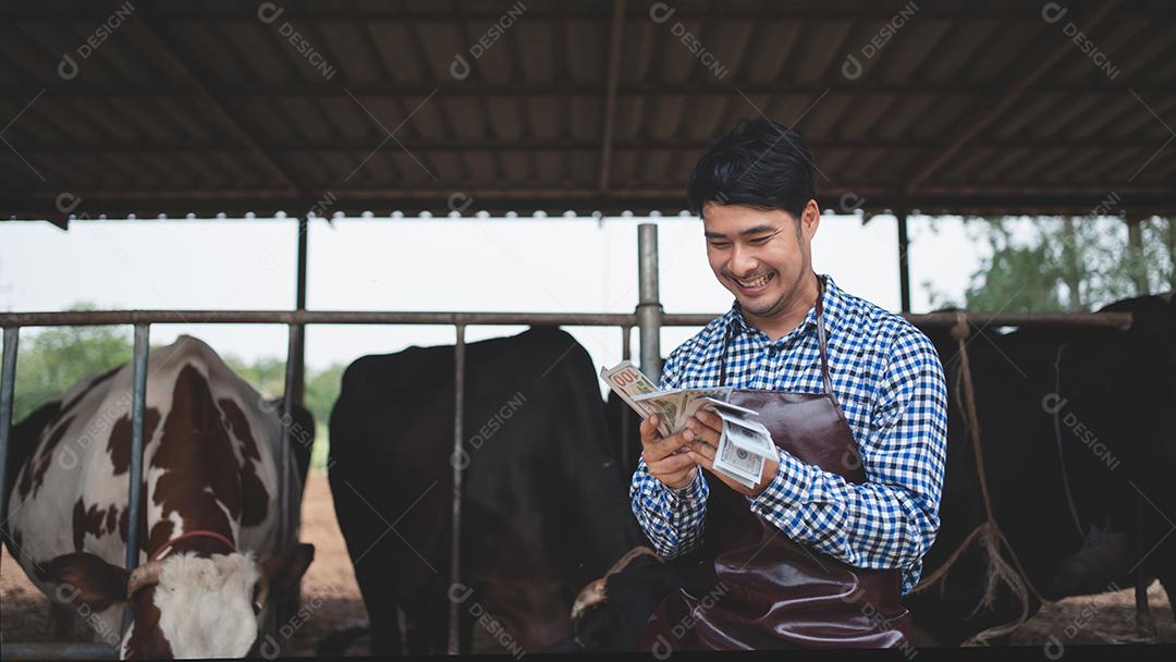 agricultores sorridentes e felizes obtêm renda da fazenda de gado leiteiro. Conceito de indústria agrícola, agricultura e pecuária, vaca na fazenda de gado leiteiro comendo feno. Estábulo.