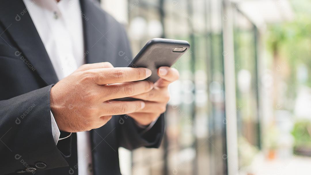 Feche o empresário digitando no telefone inteligente e sorrindo