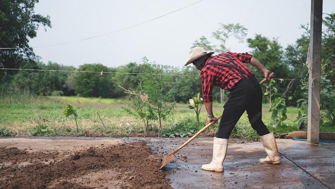 agricultor masculino limpando o gado no celeiro na fazenda de gado leiteiro. Conceito de indústria agrícola, agricultura e pecuária, vaca na fazenda de gado leiteiro comendo feno. Estábulo.