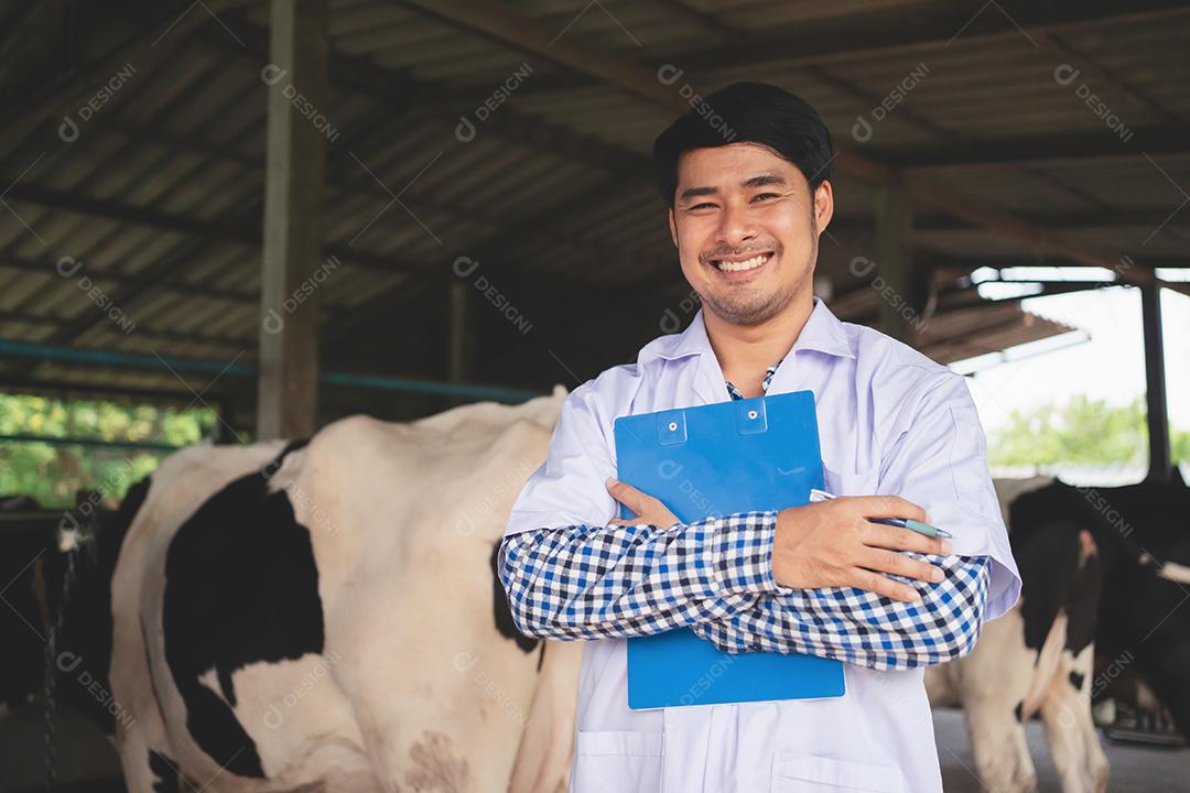 sorrindo e feliz veterinário na fazenda de gado leiteiro. Conceito de indústria agrícola, agricultura e pecuária, vaca na fazenda de gado leiteiro comendo feno.