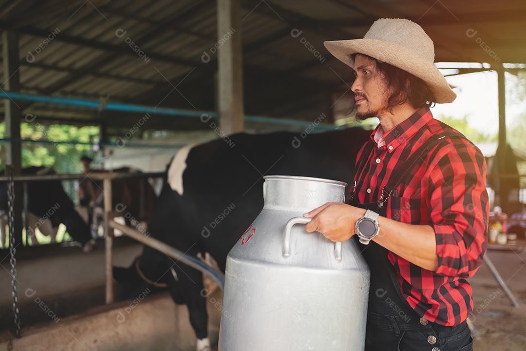 agricultor carregando um barril de leite passa pelo estábulo leiteiro., fazenda de vacas, pequenas empresas