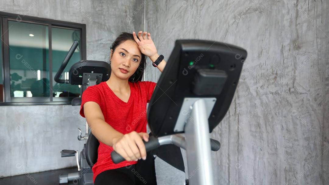 Fêmea na bicicleta de ginástica fazendo exercícios aeróbicos.