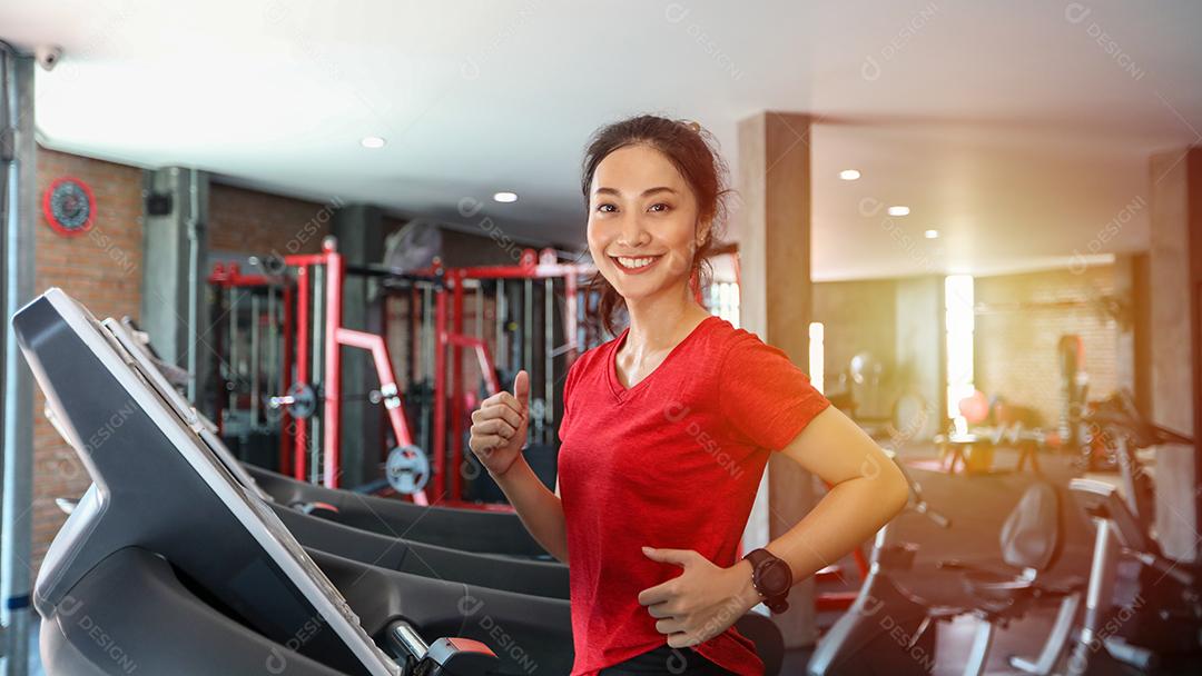 A jovem asiática está correndo na esteira