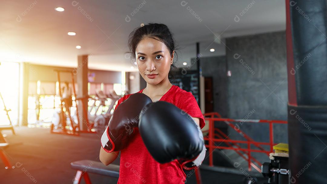 Mulheres bonitas boxeador asiático feliz e divertido fitness boxe e perfurando um saco com luvas de boxe vestindo.