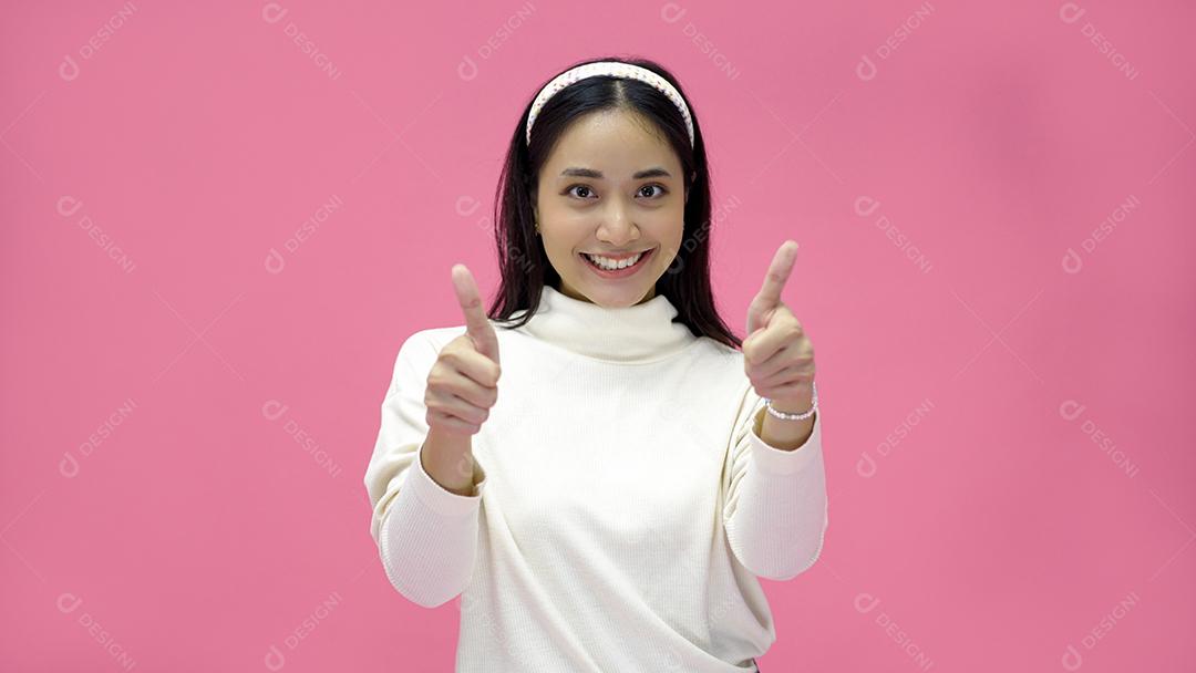 Mulher asiática sorrindo e dando os polegares para cima com alegria e emoção.