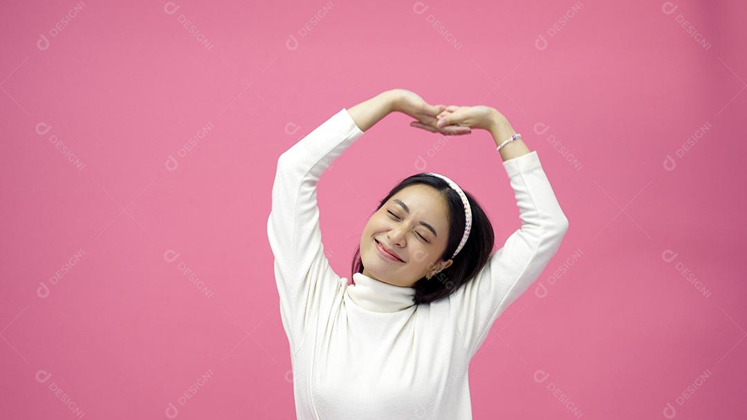 As mulheres asiáticas se exercitam e a mulher esportiva se estica na manhã, preparando-se para o treino em fundo rosa