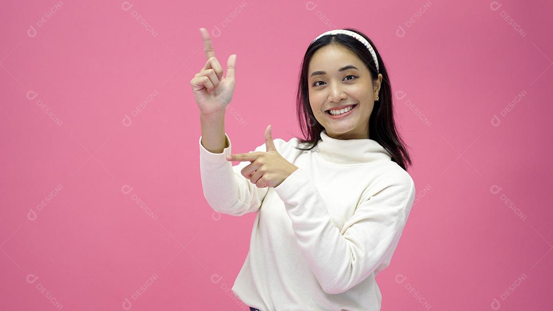 Mulher asiática feliz sorrindo e apresentando o espaço de cópia isolado no fundo rosa