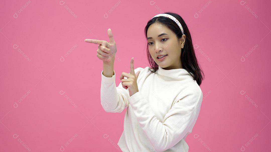 Mulher asiática feliz sorrindo e apresentando isolado no fundo rosa