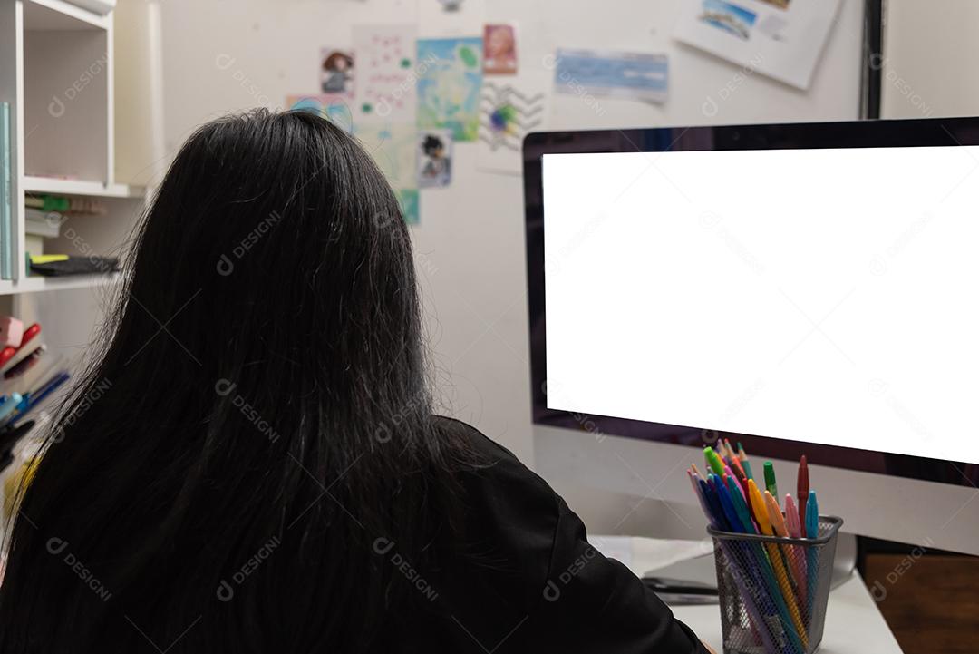 Aluna asiática está escrevendo lição de casa e lendo livro na mesa