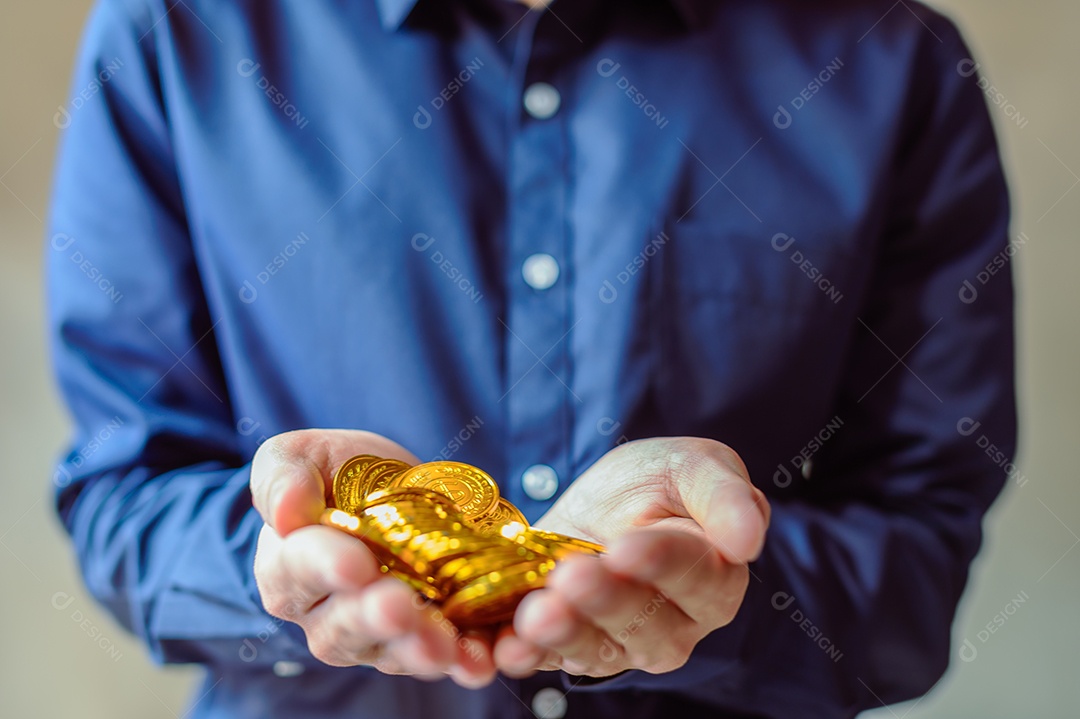 Moeda de ouro na mão do homem de negócios de camisa azul