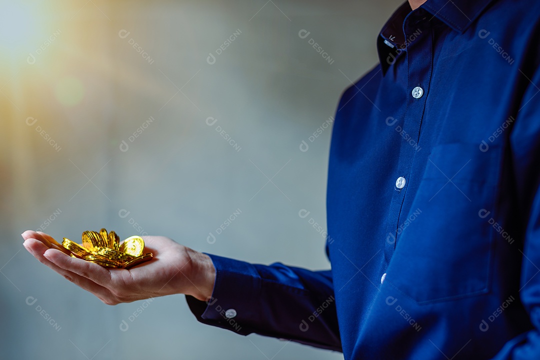 Moeda de ouro na mão do homem de negócios de camisa azul