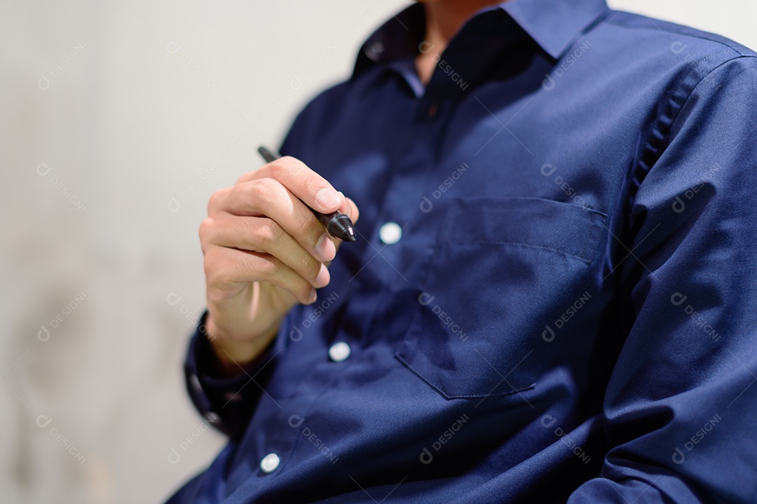 Um homem de negócios em uma camisa azul usando caneta