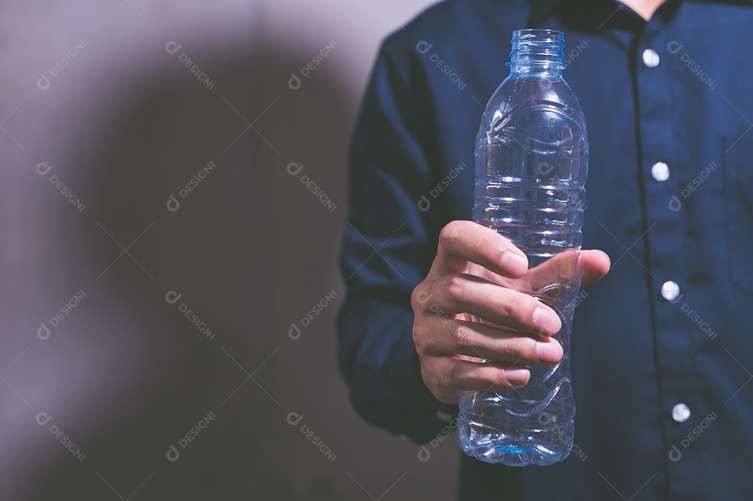 A ideia de um empresário segurando uma garrafa de água de plástico vazia