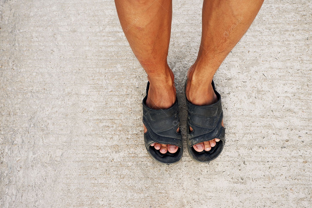 Perna do homem é usar sandálias e pé na estrada de concreto