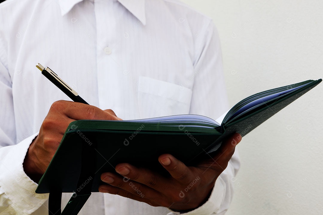 Empresário está escrevendo notas no caderno enquanto trabalha e explora algo