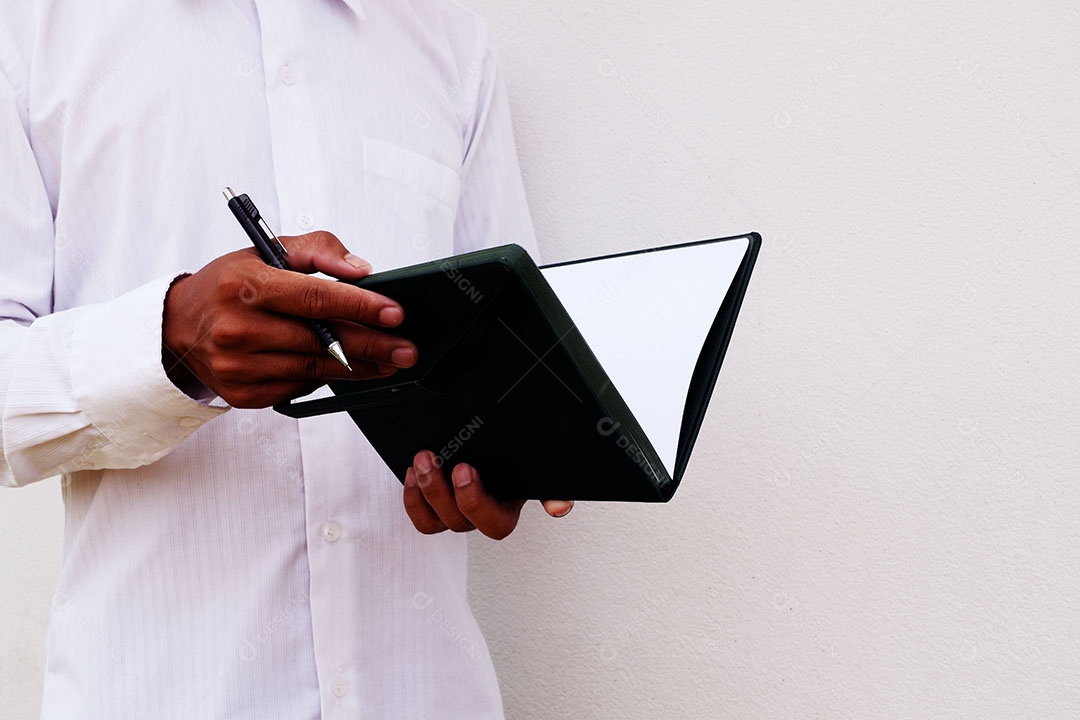 Empresário está escrevendo notas no caderno enquanto trabalha e explora algo