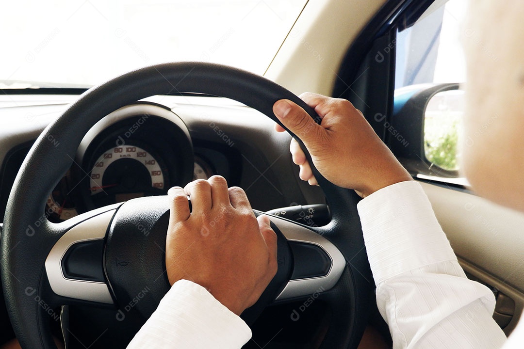 O homem está segurando o volante do carro para controlar enquanto dirige