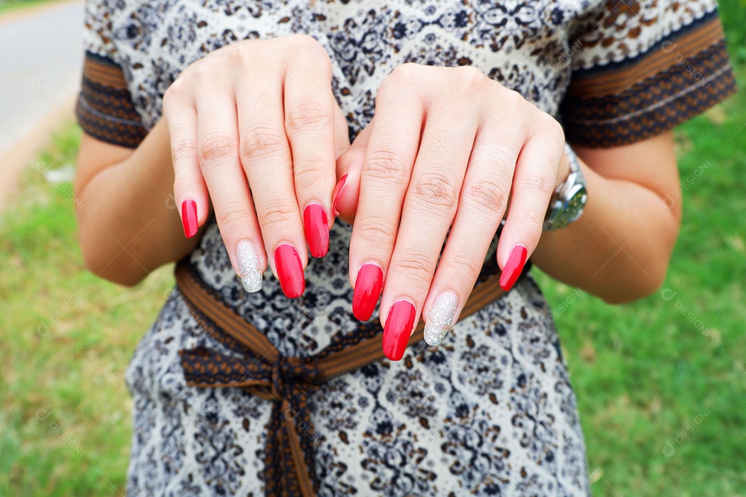 Unha pintada moda de mulher em tom vermelho Com algum dedo dos diamantes brilhantes e ela está ao ar livre
