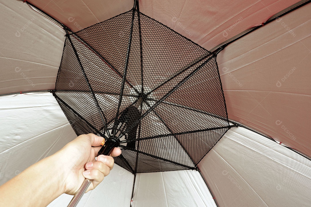 A mão segura a alça do guarda-chuva e empurra para abrir