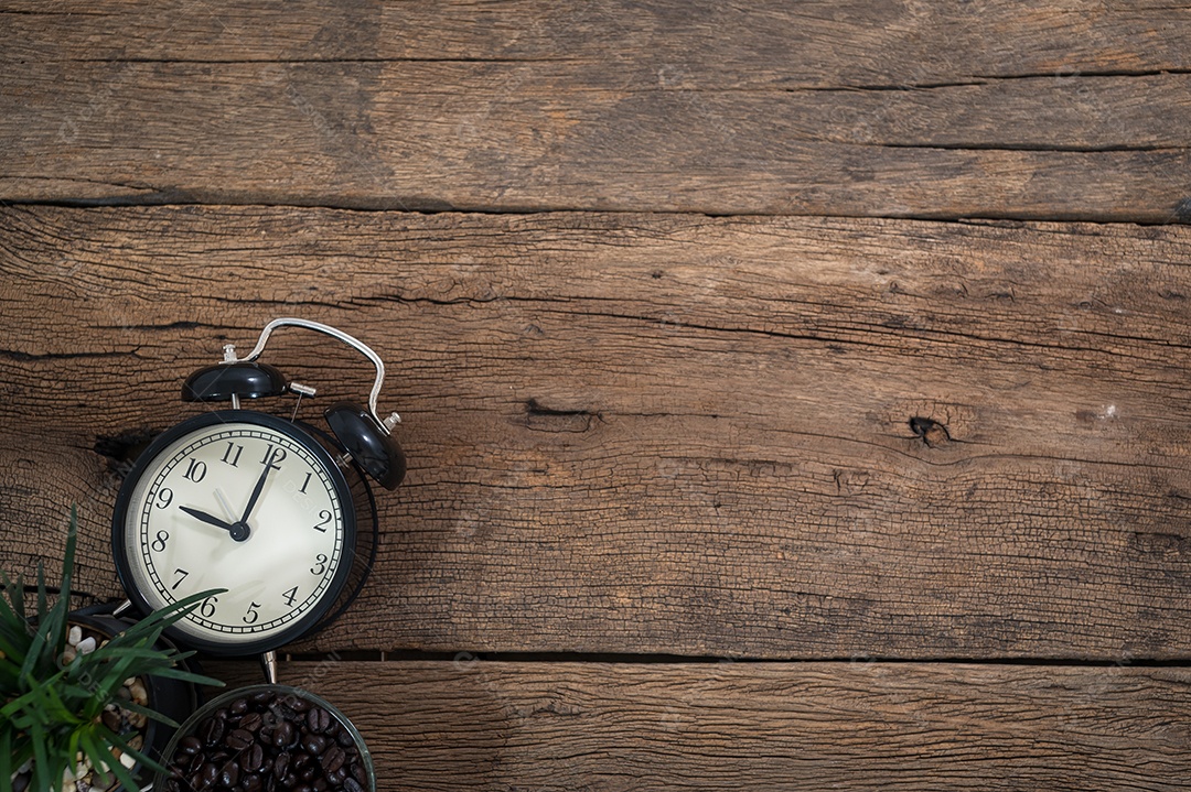 Relógio e xícara de café colocados sobre uma mesa de madeira