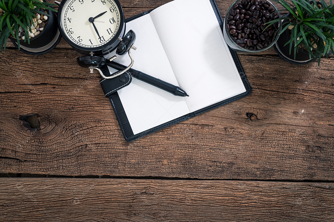 O bloco de notas e o relógio são colocados em uma mesa de madeira
