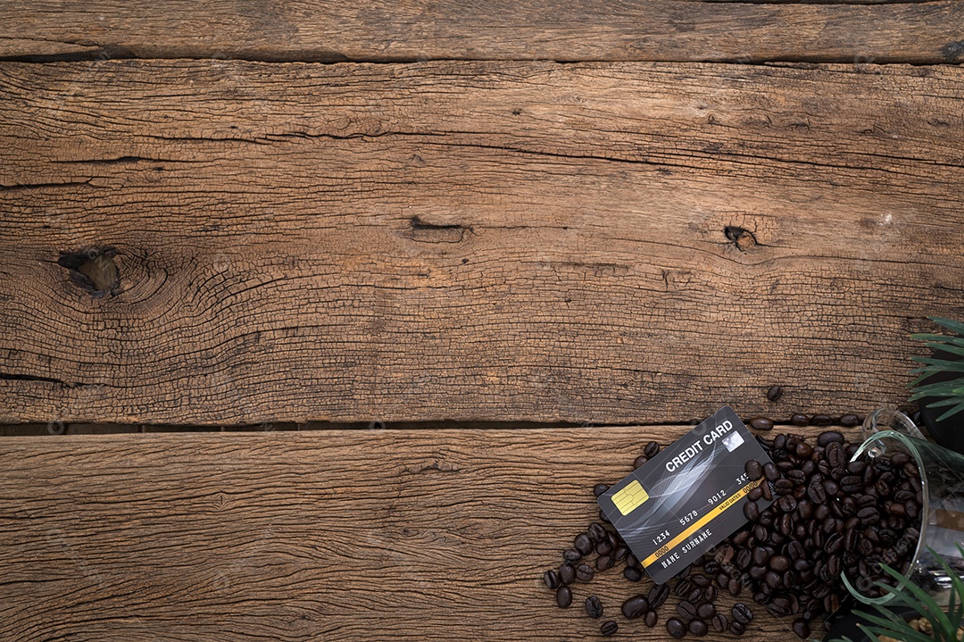 Cartão de crédito e grãos de café na vista superior da mesa
