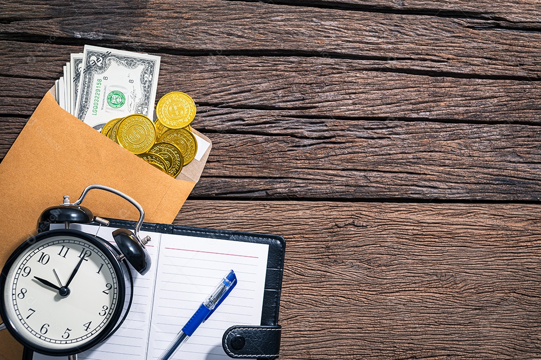 Relógio e um envelope de dinheiro, um notebook na mesa, vista superior