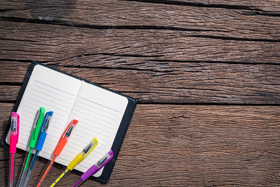 Canetas multicoloridas e bloco de notas na vista superior da mesa.