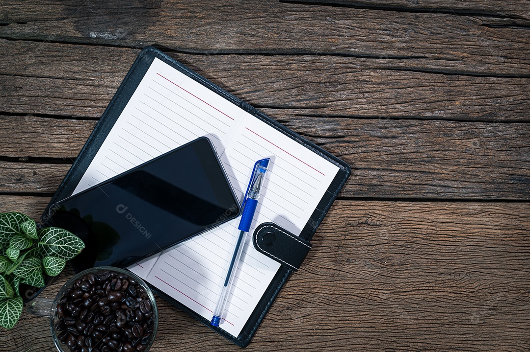 Bloco de notas de caneta de telefone inteligente colocado em uma vista superior de mesa de madeira