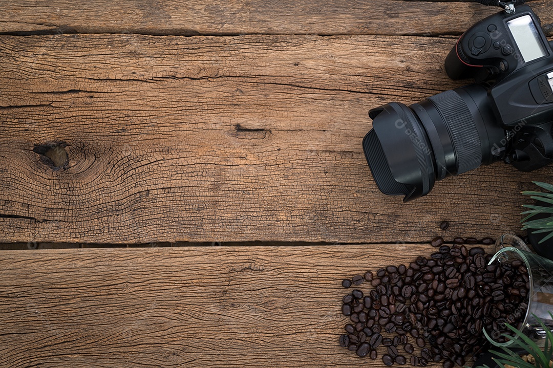 O fundo tem uma câmera, grãos de café são colocados na mesa, vista superior.