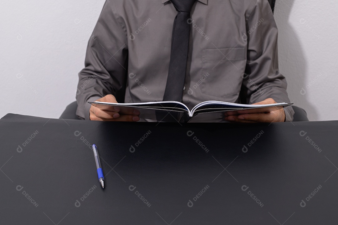 Homem de negócios que lê um livro em uma mesa