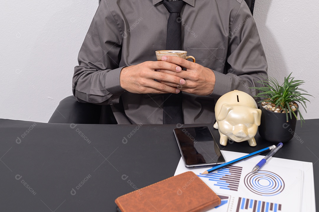 Empresário sentado em suas mesas tomando café