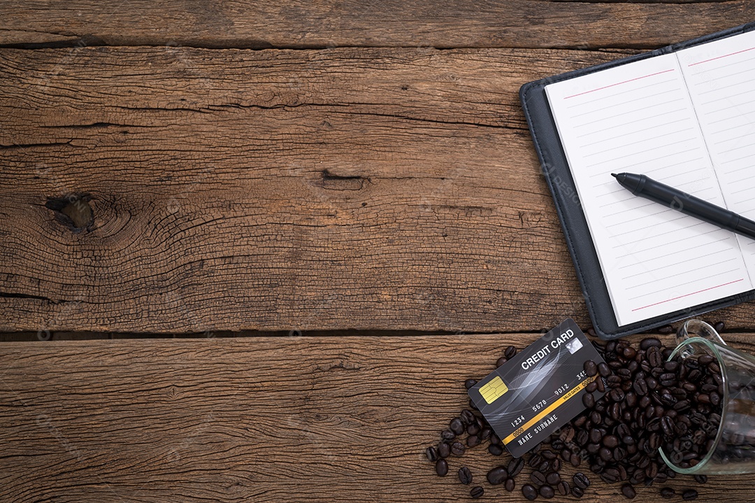 Grãos de café do caderno de cartão de crédito colocados sobre uma mesa de madeira