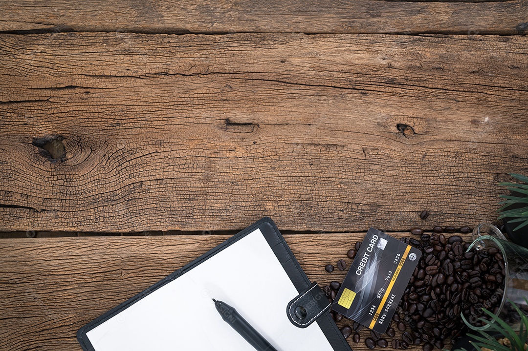 Grãos de café do caderno de cartão de crédito colocados sobre uma mesa de madeira