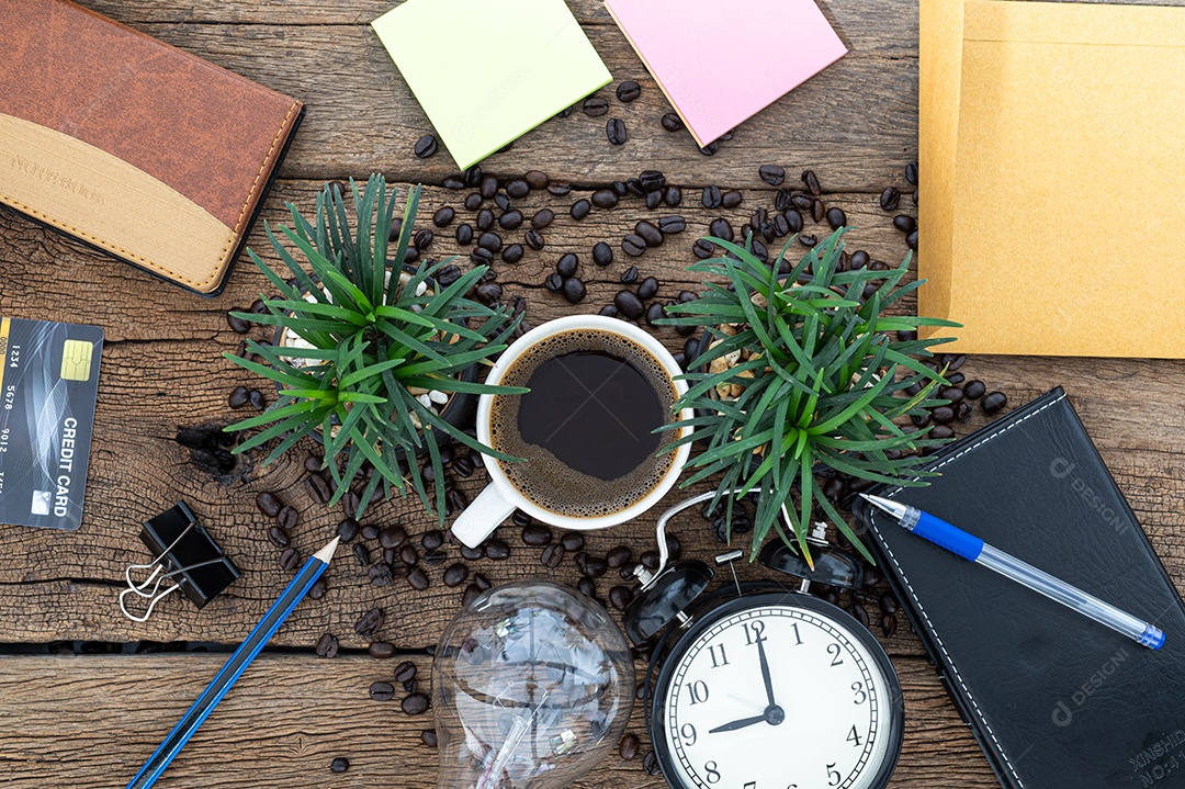 Caneca de café, papel, caderno, lápis, lâmpada, relógio na mesa, vista superior