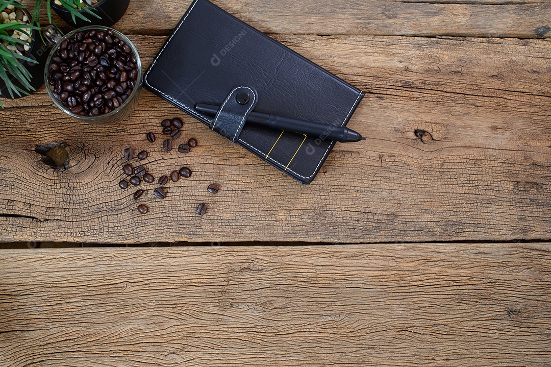 Cadernos e uma xícara de grãos de café colocados sobre uma mesa de madeira