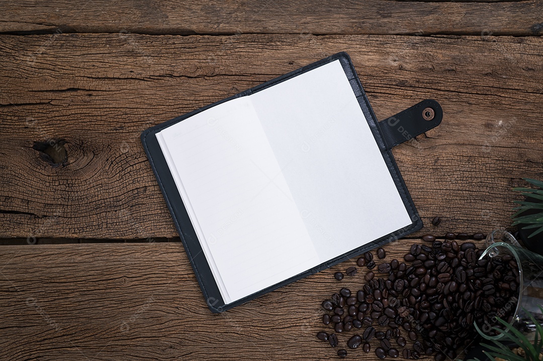 Cadernos e uma xícara de grãos de café colocados sobre uma mesa de madeira