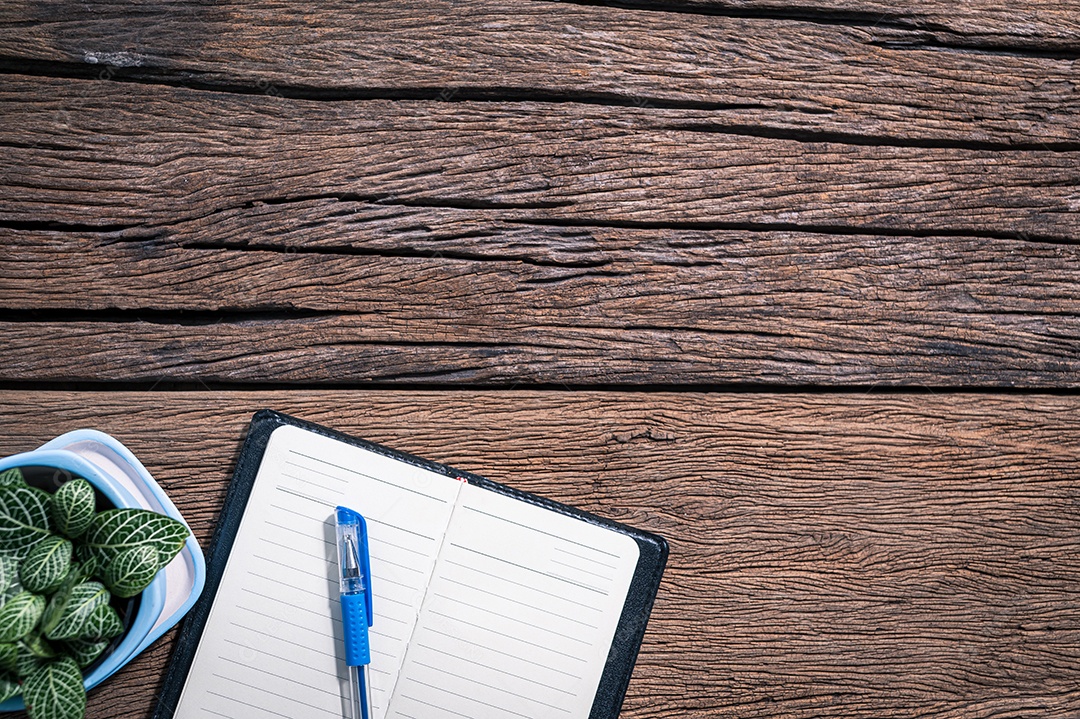 O bloco de notas e o relógio são colocados em uma mesa de madeira