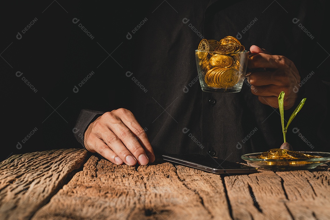 Empresário segura um copo com moedas e assiste a um smartphone