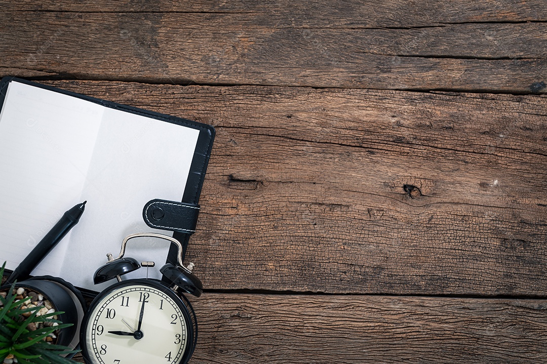 O bloco de notas e o relógio são colocados em uma mesa de madeira