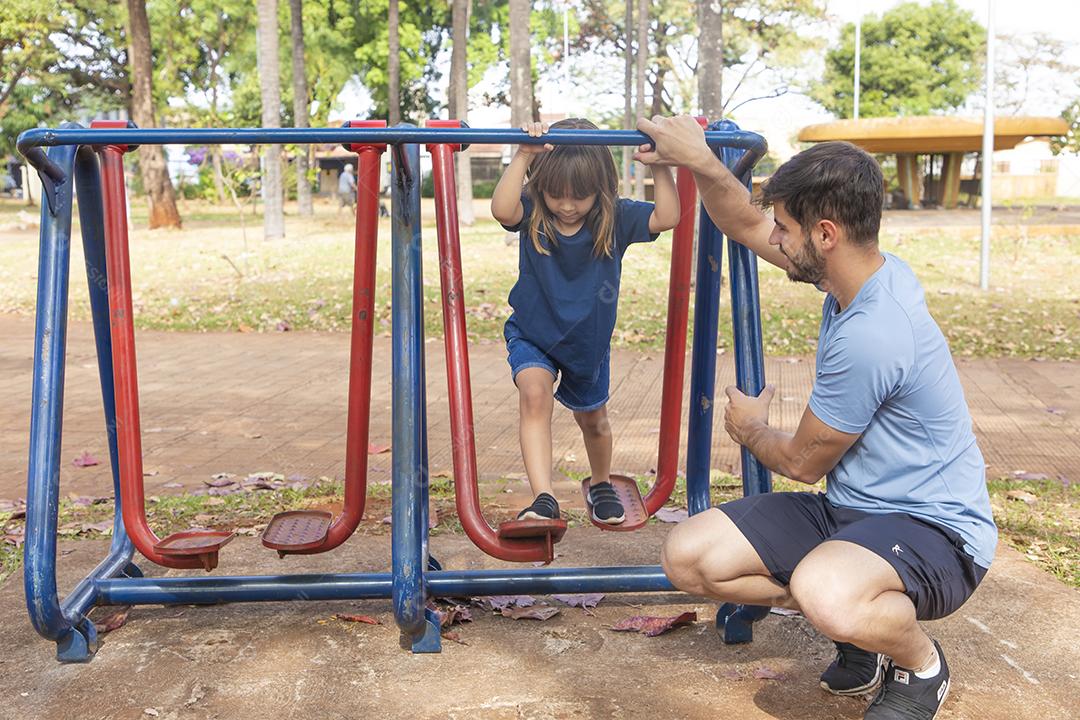 pai e filha fazendo exercício em aparelhos ao ar livre