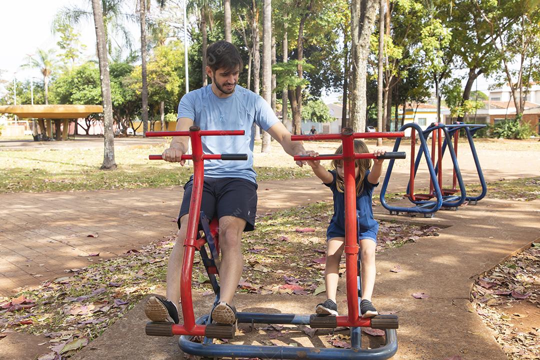 pai e filho fazendo exercício em aparelhos ao ar livre com filha