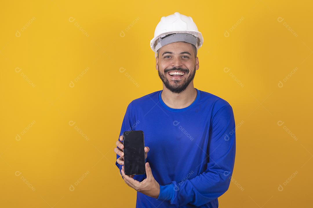 Arquiteto de homem bonito segurando smartphone com tela em branco com espaço livre para texto em fundo amarelo