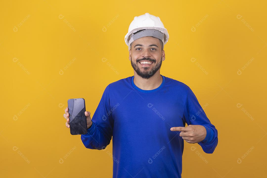 Arquiteto de homem bonito segurando smartphone com tela em branco com espaço livre para texto em fundo amarelo