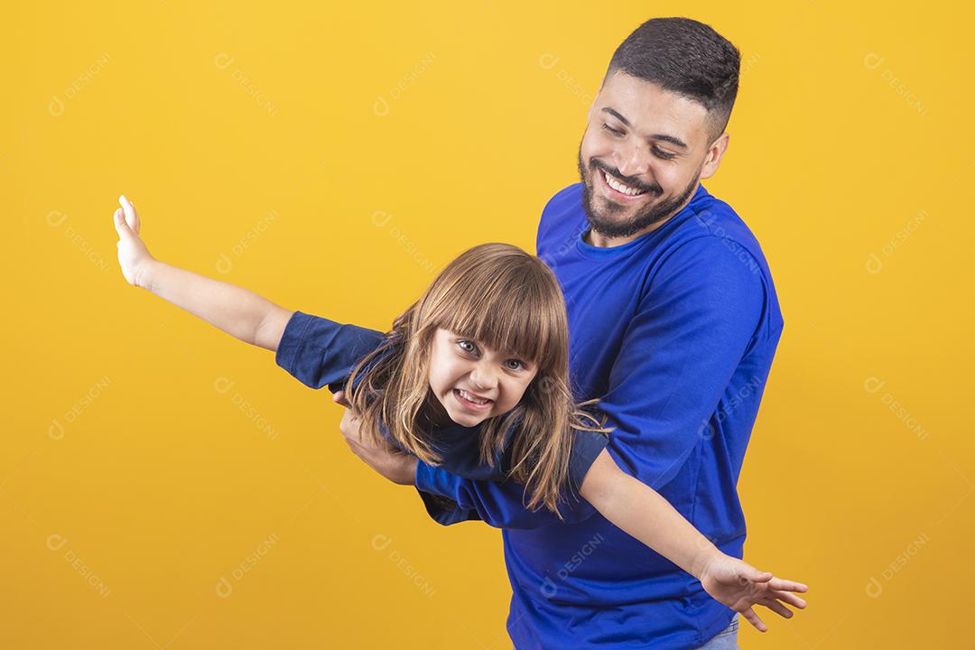 Menina alegre brincando com o pai em background amarelo