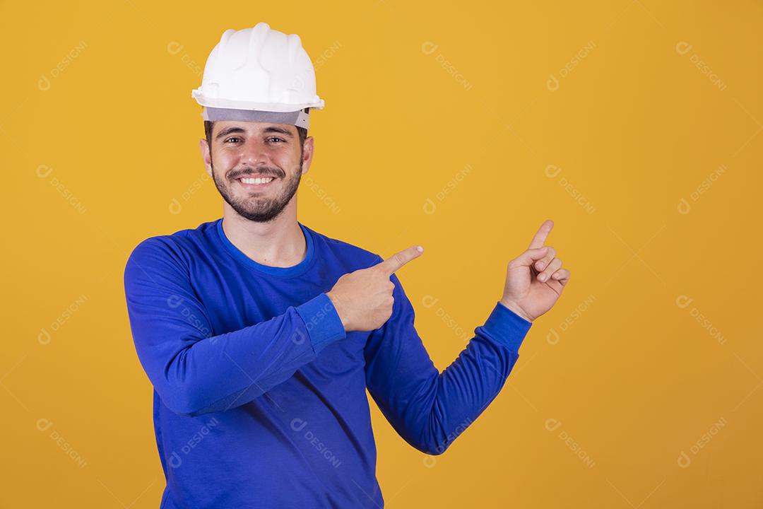 Homem jovem arquiteto com capacete apontando para o lado