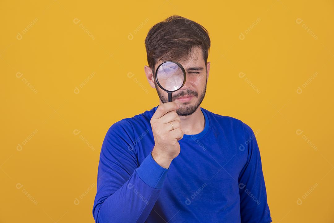 jovem detetive masculino segurando a lupa pelo olho direito enquanto