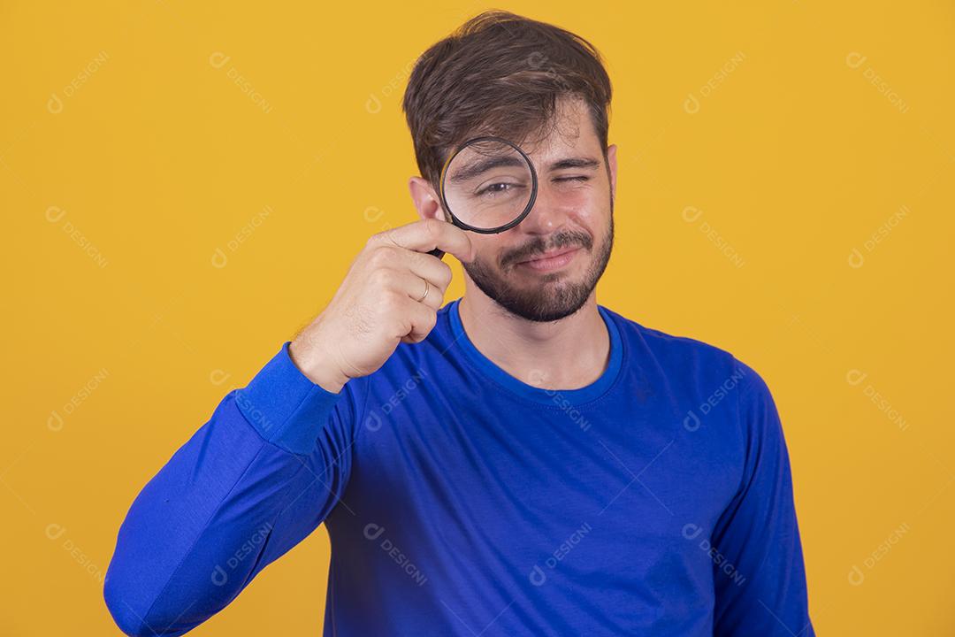 jovem detetive masculino segurando a lupa pelo olho direito enquanto