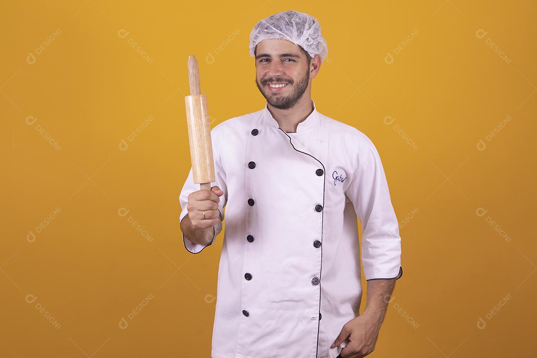 homem chef de cozinha segurando uma esponja de lavar louça e um prato sob fundo amarelo